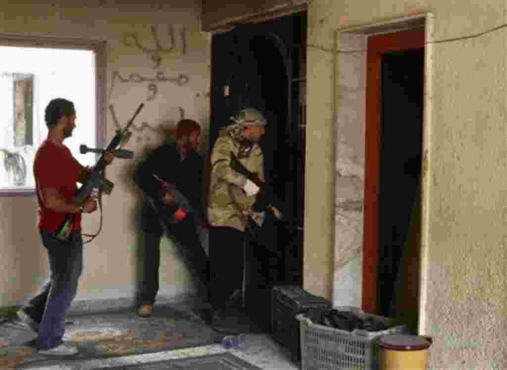 Combatientes rebeldes en búsqueda de un edificio de las fuerzas pro-Gadafi en la ciudad sitiada de Misrata, Libia, 23 de abril 2011.