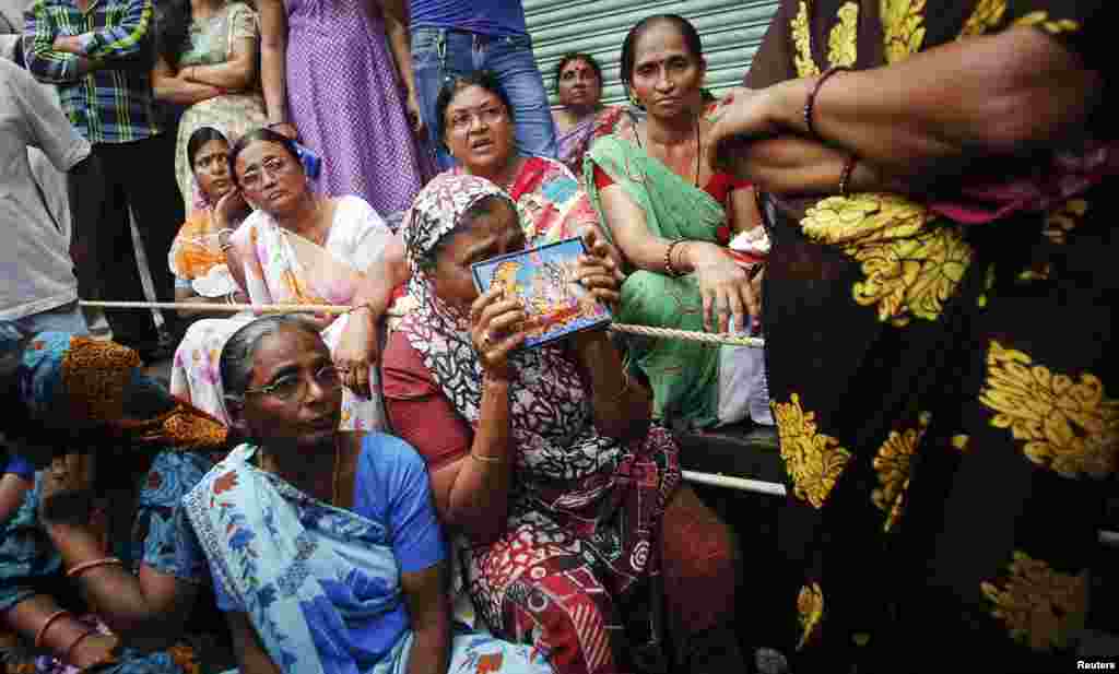 Seorang perempuan berdoa bagi para kerabatnya yang terjebak di dalam reruntuhan gedung apartemen yang ambruk di Mumbai (27/9).