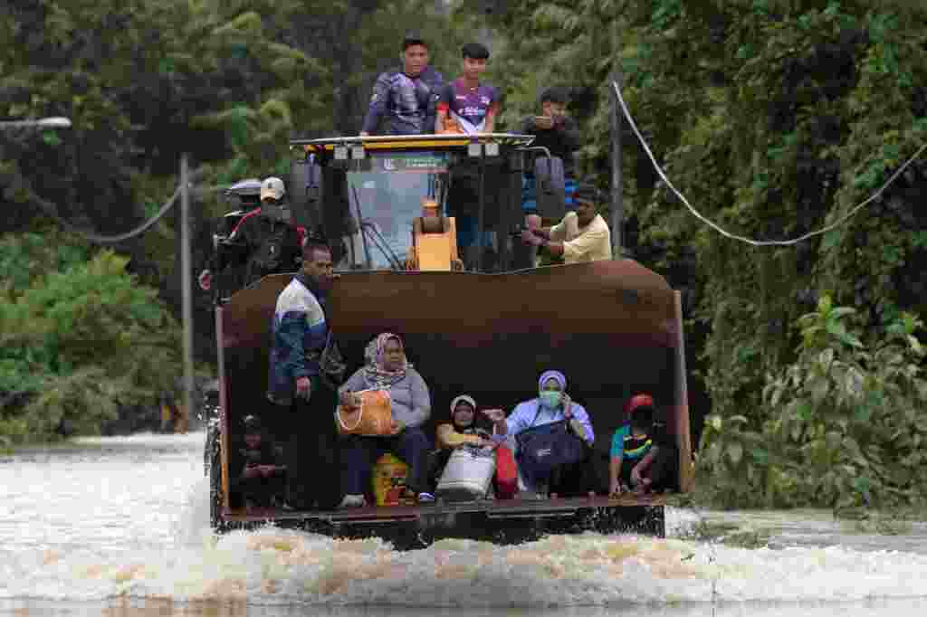 Residents ride a digger vehicle through floodwaters following heavy monsoon downpour in Lanchang, Malaysia&#39;s Pahang state.