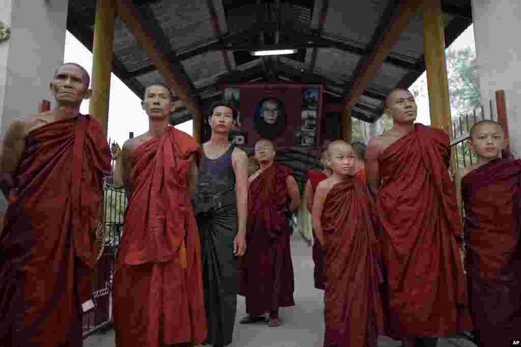 Tu sĩ Phật giáo đứng chờ để được nhìn thấy lãnh tụ dân chủ Aung San Suu Kyi khi bà đến thăm một trạm bỏ phiếu gần tu viện trong thị trấn Kawhmu, ngày 1/4/2012 (Reuters)