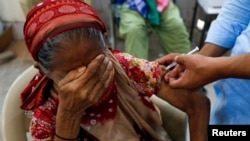 FILE - Basanti, 71, reacts as she receives a dose of the coronavirus disease (COVID-19) vaccine at a vaccination center in Karachi, Pakistan, June 9, 2021.