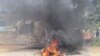 FILE - A barricade is set ablaze in the road during a protest in Mbabane, Eswatini, June 29, 2021. 