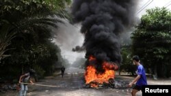 Un manifestant passe devant des pneus en feu après que des militants ont lancé une "grève des ordures" contre le régime militaire, à Yangon, au Myanmar/Birmanie, le 30 mars 2021. 