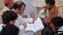 Naim ullah Khattak (L), an Election Commission of Pakistan (ECP) worker, verifies voters using a list from the Computerized National Identity Card (CNIC) database in the outskirts of Islamabad on Sept. 12, 2011.