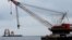 FILE - A construction crane floats next to a barge carrying jacket support structures and a platform for a turbine for a wind farm off Block Island, Rhode Island, July 27, 2015.