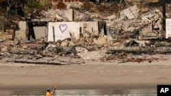 A kayaker goes past a row of homes damaged by the Palisades Fire, Jan. 15, 2025, in Malibu, Calif. 