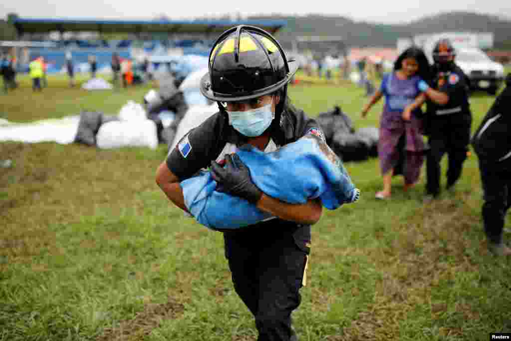 A firefighter carries a baby rescued along with her mother from an area affected by mudslides caused by Storm Eta, in San Cristobal Verapaz, Guatemala, Nov. 7, 2020.