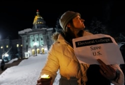 FILE - Ruth Fulton demonstrates during a candlelight vigil against then-U.S. President-elect Donald Trump outside the Colorado Capitol on the eve of the Electoral College vote, in Denver, Dec. 18, 2016.