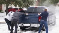 Residents help a pickup driver get out of ice on the road in Round Rock, Texas, on February 17, 2021, after a winter storm.