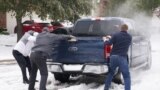 Residents help a pickup driver get out of ice on the road in Round Rock, Texas, on February 17, 2021, after a winter storm. 