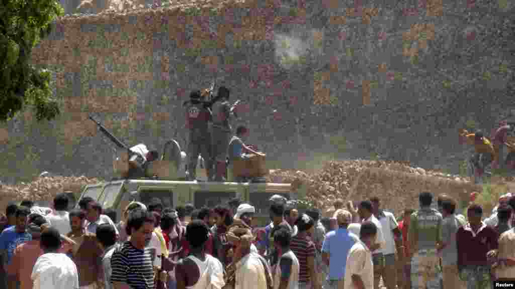 People loot weapons and ammunition from the army depot in Aden, March 27, 2015.