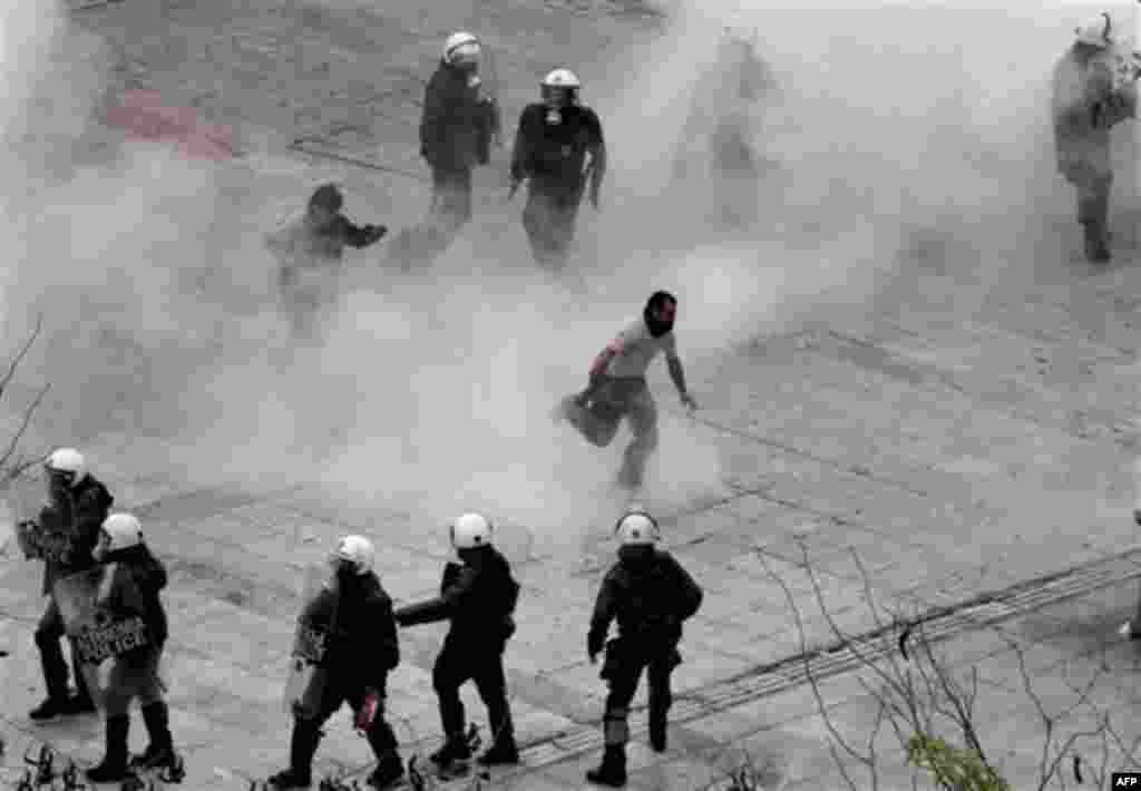 Protesters, center, run to avoid tear gas as riot police officers react during clashes in central Athens, Wednesday, Dec. 15, 2010. Hundreds of protesters clashed with riot police across central Athens Wednesday, smashing cars and hurling gasoline bombs d