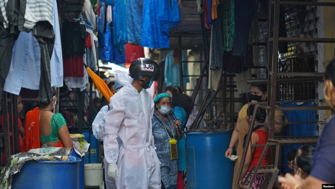 A worker wearing a 'Smart Helmet' thermoscanner that measures the temperature of people at a distance, screens residents in a slum Mumbai, India, July 23, 2020.