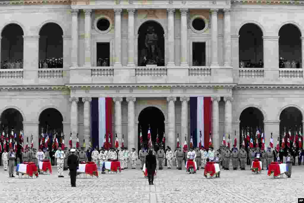 French President Emmanuel Macron bows to coffins during a ceremony for the 13 French soldiers killed in Mali, at the Invalides monument in Paris.