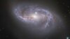 FILE - Looking deep into the Universe, the NASA/ESA Hubble Space Telescope catches a passing glimpse of the numerous arm-like structures that sweep around this barred spiral galaxy, known as NGC 2608. 