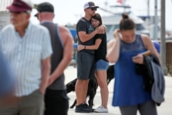 Two people hug as they they look over a makeshift memorial near Truth Aquatics as the search continues for those missing in a pre-dawn fire that sank a commercial diving boat near Santa Barbara, California, Sept. 3, 2019.