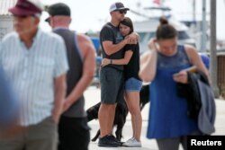 Two people hug as they they look over a makeshift memorial near Truth Aquatics as the search continues for those missing in a pre-dawn fire that sank a commercial diving boat near Santa Barbara, California, Sept. 3, 2019.