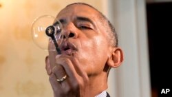 President Barack Obama blows a soap bubble using a 3-D printed bubble wand designed by Jacob Leggette, 9, of Baltimore, Md., while touring the 2016 White House Science Fair at the White House in Washington, Wednesday, April 13, 2016. 