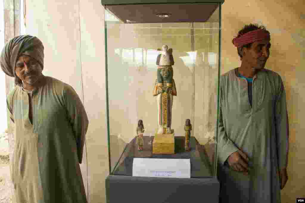 Pekerja penggalian menjaga patung kayu Isis-Nefertiti, istri Ramses II, yang dipamerkan dekat sebuah makam baru yang dikenal sebagai Kampp 161, dalam sebuah acara pengumuman mengenai penemuan tersebut oleh Kementerian Peninggalan Purbakala Mesir, di Luxor, Mesir, ( Desember 2017. (H. Elrasam/VOA)
