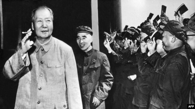 历史照片：中共最高领导人毛泽东（1893-1976）拿着烟卷，林彪紧随其后，其他人挥动着《毛主席语录》。(1970年9月初)
