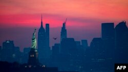 Patung Liberty digambarkan di depan Lower Manhattan sebelum matahari terbit di tengah pandemi virus corona pada 19 Juli 2020 di New York City. (Foto: AFP/Johannes Eisele)
