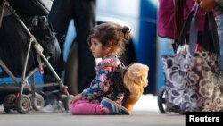 A migrant girl waits to board a bus after arriving by train at Schoenefeld railway station, south of Berlin, Germany, September 13, 2015. 