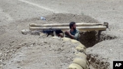 An Afghanistan National Army soldier stands guard in a trench in district of Baraki Barak in Logar province, east of Kabul, Afghanistan, July 20, 2015. 