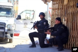 Tunisian police officers take positions as they search for attackers still at large in the outskirts of Ben Guerdane, southern Tunisia, March 8, 2016.