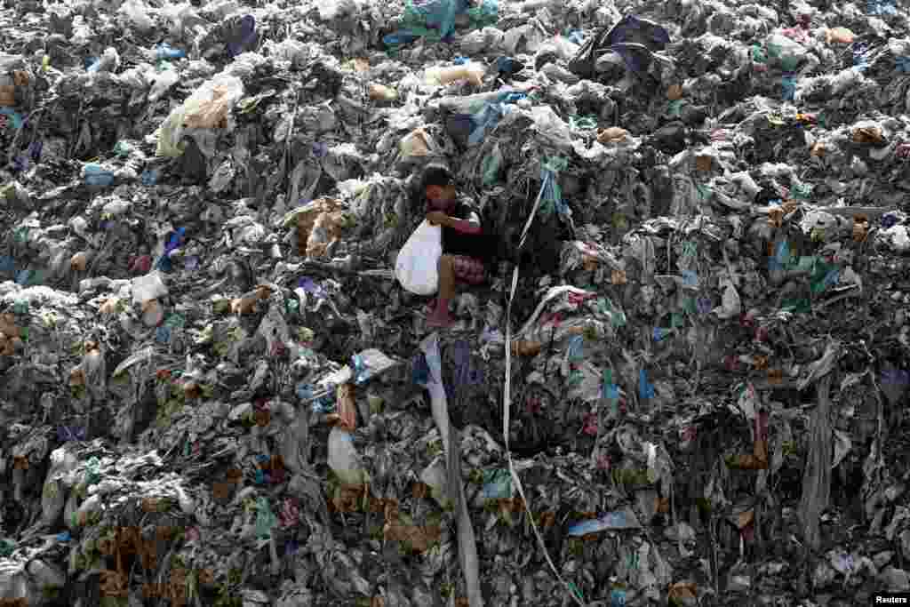 Seorang bocah pemulung mencari barang-barang yang bisa di daur ulang di tempat pembuangan sampah di Phnom Penh, Kamboja.