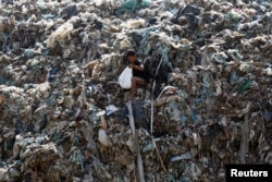 FILE - A boy collects metal and wire for recycling at a dump site in Phnom Penh, Cambodia, May 24, 2016.