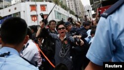 A plainclothes policeman wields a baton during a confrontation between protesters demonstrating against mainland traders and local residents, at Yuen Long district near the border with mainland China, in Hong Kong, March 1, 2015. 