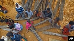 Young Somali refugees read verses of the Koran from their prayer tablets at an outdoor madrasa at the Ifo camp outside Dadaab, Eastern Kenya, 100 kms (60 miles) from the Somali border, Aug. 9, 2011.