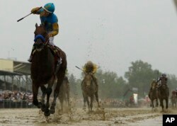 American Pharoah pulls away near the end of the race, which was run in heavy rain and very sloppy conditions. He'll go for horse racing's Triple Crown in the Belmont Stakes next month.