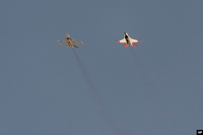 An AI-enabled U.S. Air Force F-16 fighter jet, the X-62A VISTA, right, flies nose to nose with an adversary F-16, as both aircraft raced within 1,000 feet of each other, May 2, 2024, above Edwards Air Force Base, Calif. (AP Photo/Damian Dovarganes)