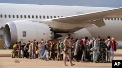 Des Afghans qui ont été transportés d'Afghanistan, marchent après avoir débarqué d'un avion, à la base militaire de Torrejon dans le cadre du processus d'évacuation à Madrid, le. 23 août 2021.