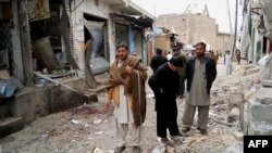 Onlookers stand over the site of a bomb blast outside a Shiite Muslim mosque in Hangu, February 1, 2013.