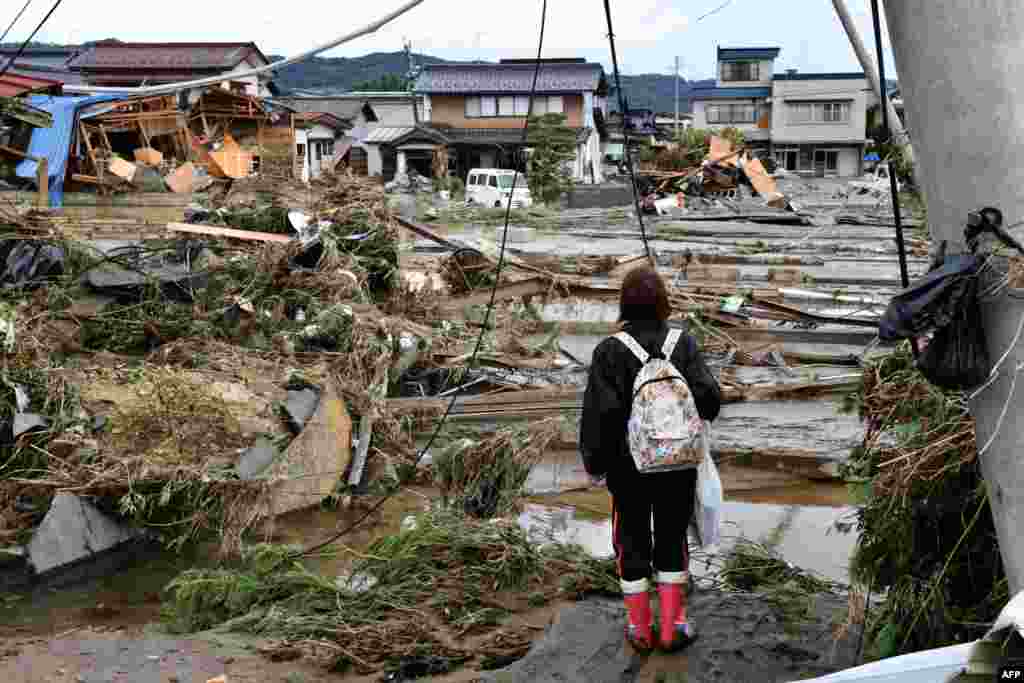 A woman looks at flood-damaged homes in Nagano, after Typhoon Hagibis hit Japan, unleashing high winds, torrential rain and triggered landslides and catastrophic flooding.