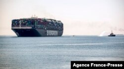 FILE - The Panama-flagged MV 'Ever Given' container ship sails past a tugboat spraying a jet of water along Egypt's Suez Canal near the canal's central city of Ismailia, July 7, 2021. 