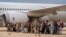 Des Afghans qui ont été transportés d'Afghanistan, marchent après avoir débarqué d'un avion, à la base militaire de Torrejon dans le cadre du processus d'évacuation à Madrid, le. 23 août 2021.