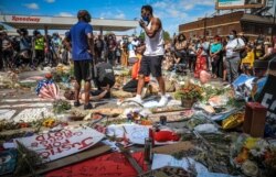 El organizador de la comunidad Tommy McBrayer, a la derecha, usa un megáfono mientras dirige una recreación del encuentro de George Floyd con la policía.