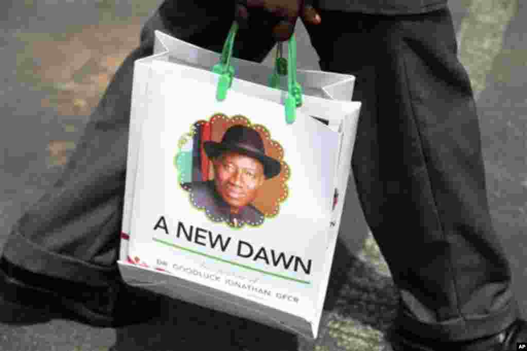 A man carries a bag with the portrait of Nigerian President Goodluck Jonathan during his inauguration ceremony at the main parade ground in Nigeria's capital of Abuja Sunday, May 29, 2011. Goodluck Jonathan was sworn in Sunday for a full four-year term as