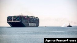 FILE - The Panama-flagged MV 'Ever Given' container ship sails past a tugboat spraying a jet of water along Egypt's Suez Canal near the canal's central city of Ismailia, July 7, 2021. 