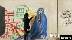 Afghan artist Malina Suliman paints graffiti on a wall in Kandahar city December 30, 2012.
