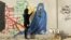 An Afghan artist Malina Suliman paints graffiti on a wall in Kandahar city December 30, 2012.