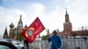 Seorang pria berpose dengan bendera merah di depan Lapangan Merah dalam peringatan 75 tahun kekalahan Nazi dalam Perang Dunia Kedua di Moskow, Rusia, 9 Mei 2020.