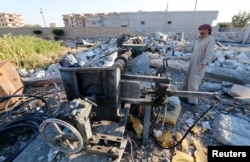 Abu Ismail, the owner of a plastics factory that was targeted by what activists said were U.S.-led air strikes, gestures while standing at his destroyed factory in the Islamic State's stronghold of Raqqa, Sept. 29, 2014.