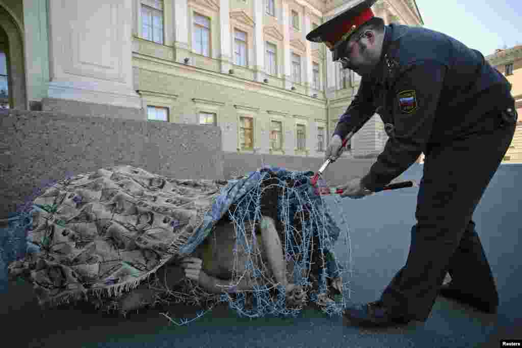 Artist Pyotr Pavlensky lies on the ground, wrapped in barbed wire roll, during a protest action in front the Legislative Assembly of Saint Petersburg, Russia, aiming to express his view that the legislative system of the city is oppressive, according to local media. 