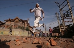 FILE - Kashmiris run for cover as Indian security forces (not pictured) fire tear gas shells during clashes, after scrapping of the special constitutional status for Kashmir by the Indian government, in Srinagar.