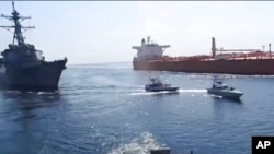 FILE - This frame grab from a video released by Iran's Revolutionary Guard on Nov. 3, 2021, shows Guard boats, center, near a U.S. warship, left, amid the seizure of an oil tanker, right, in the Gulf of Oman. The U.S. Navy said it stopped the seizure of two tankers July 5, 2023.