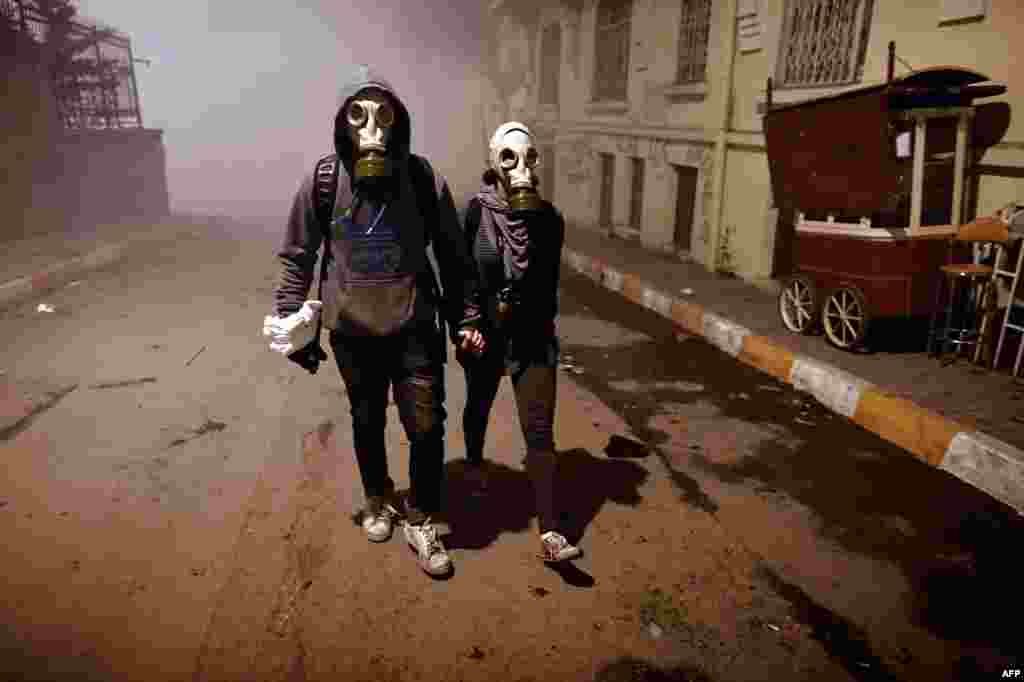 A couple wearing gas masks walk at a street between Taksim and Besiktas in Istanbul during a demonstration against the demolition of the park, June 4, 2013. 